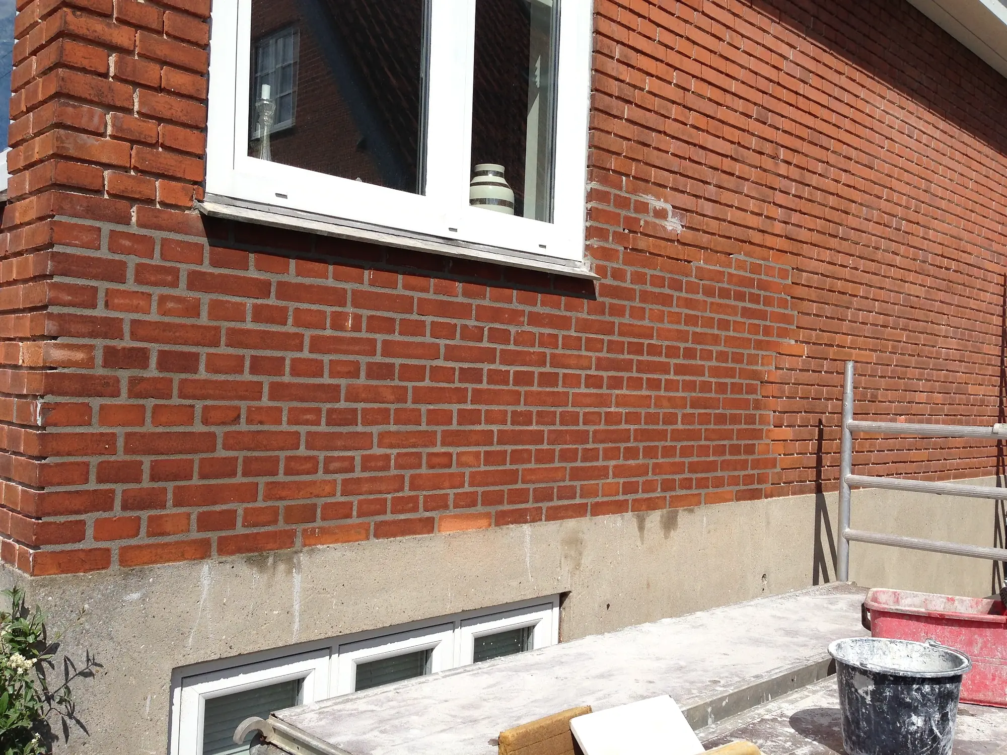 Omfugning af rød murstensfacade under udførelse